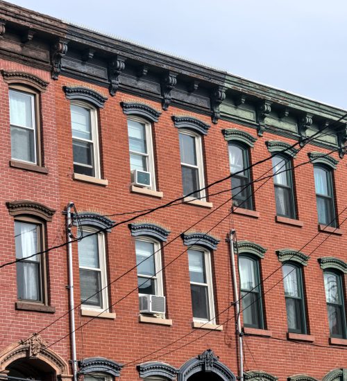 jersey city brownstone building detail (historic pre-war red brick buildings with power lines) beautiful real estate apartment homes with cornice decor urban city life window detail close up family